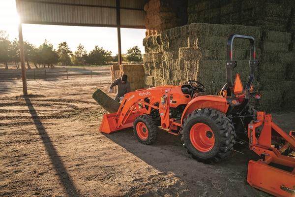 Man loading tractor bucket of hay stacks