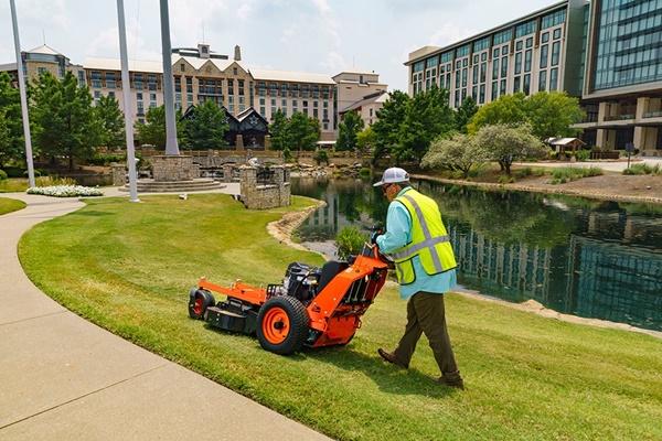 Landscaper mowing lawn with walk-behind mower