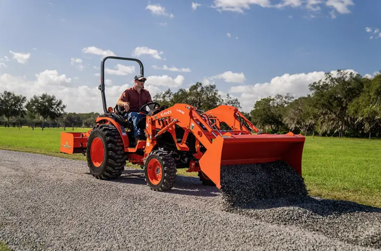 Man using tractor to dumb gravel onto driveway