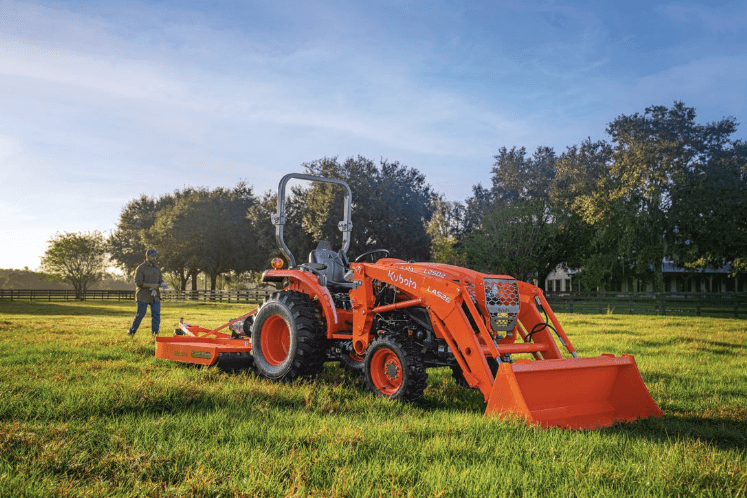 Man walking behind tractor in a field