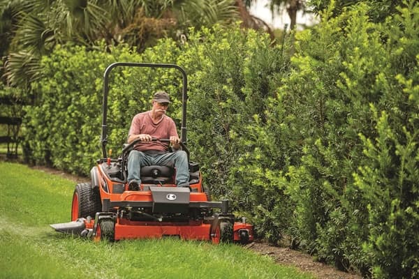 Man mowing lawn close up to hedges