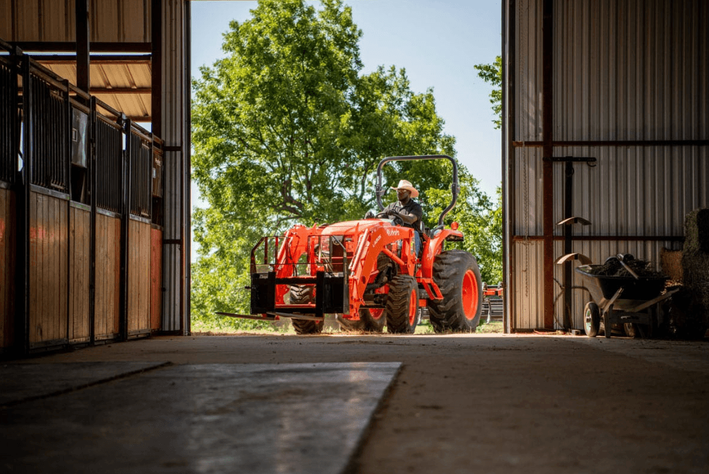 Man driving tractor into barn