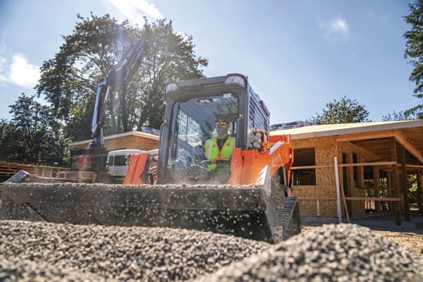 Close-up of man moving gravel with track loader