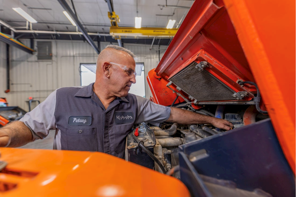 man working under hood of kubota equipment